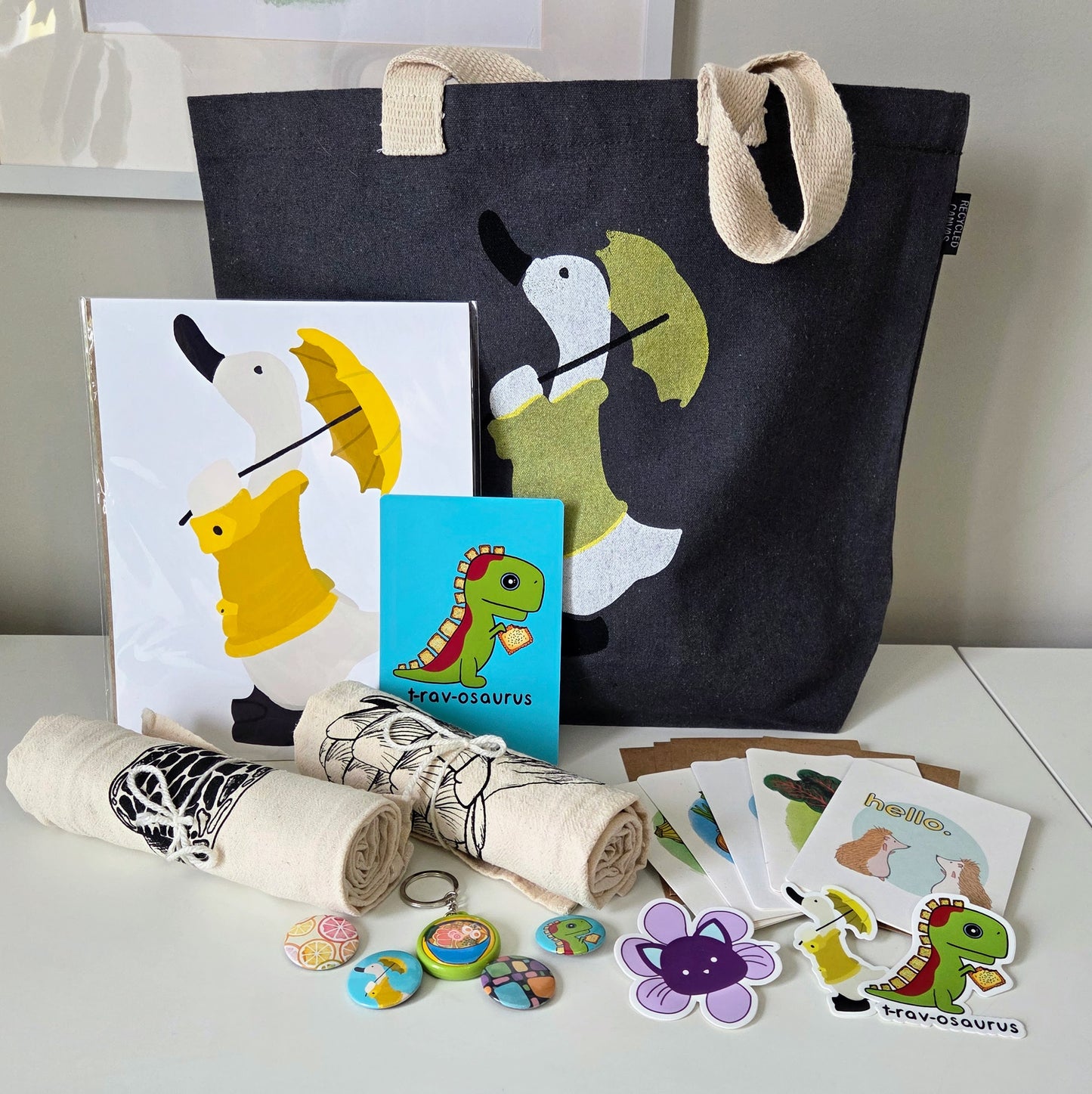 Collection of items including a tote bag, cards, and stickers on a white surface.